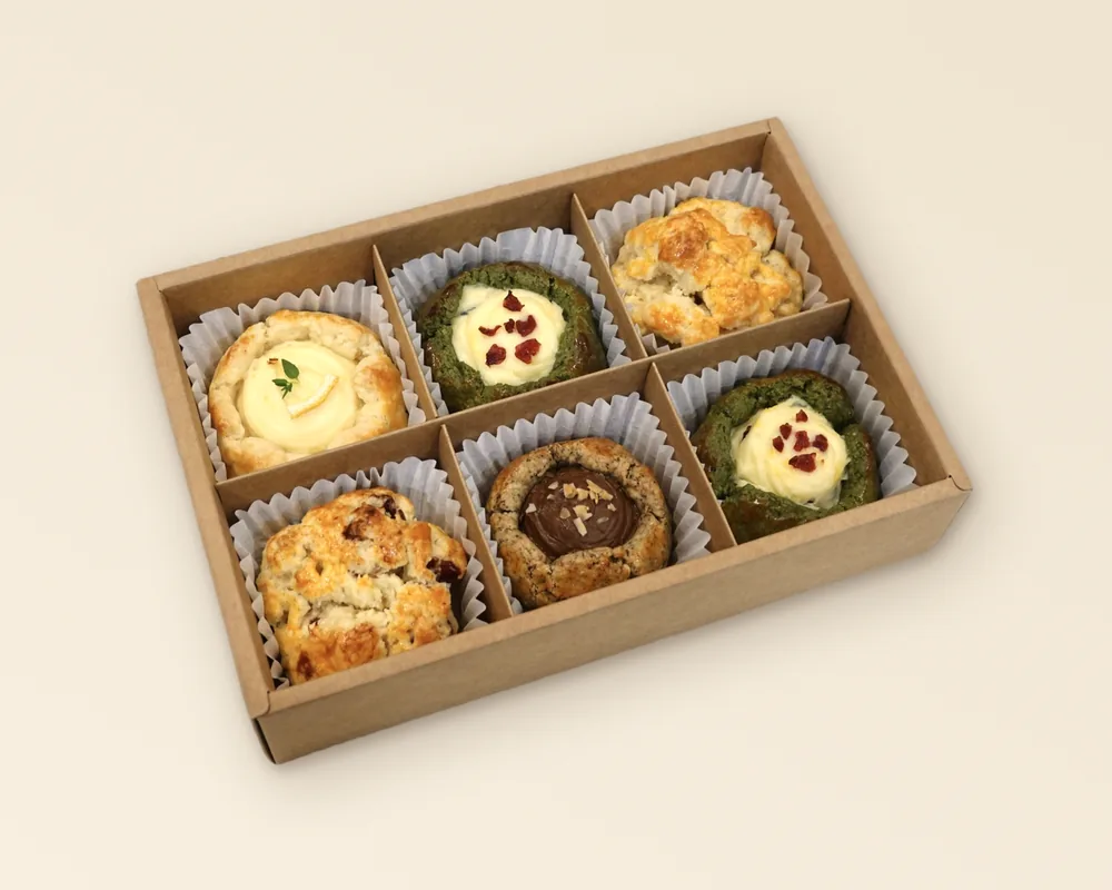 An open kraft SCOF gift box with six compartments, a scone in a paper case in each — one example of a chosen six, not a fixed selection.