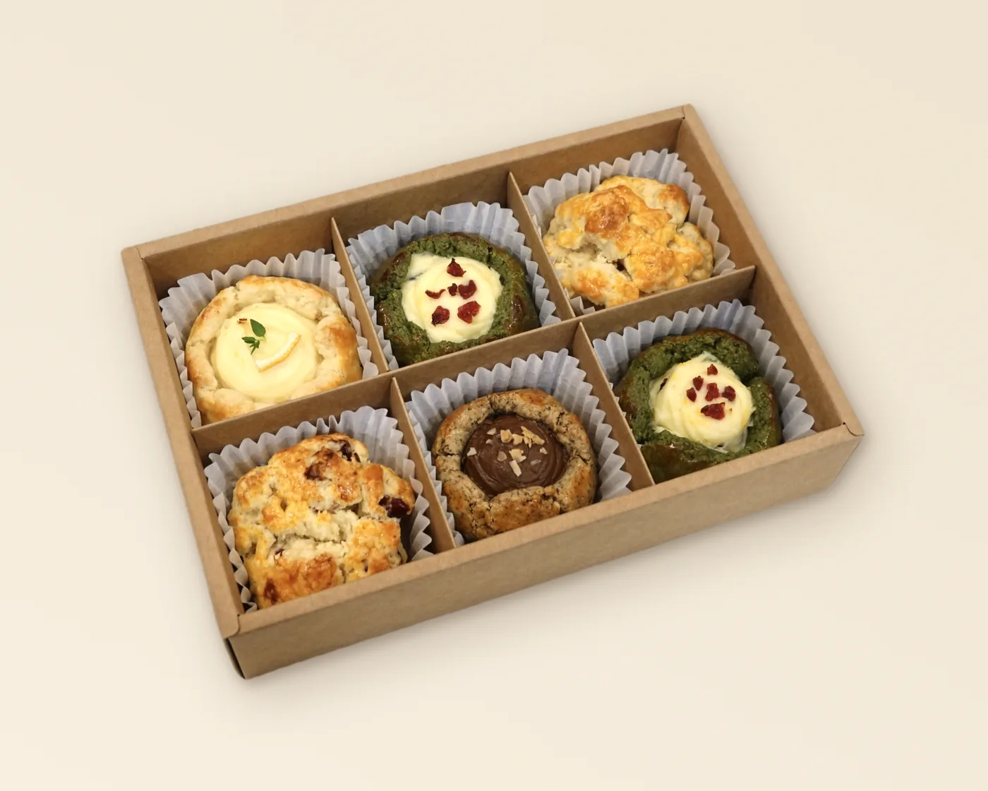 An open kraft SCOF gift box with six compartments, a scone in a paper case in each — one example of a chosen six, not a fixed selection.