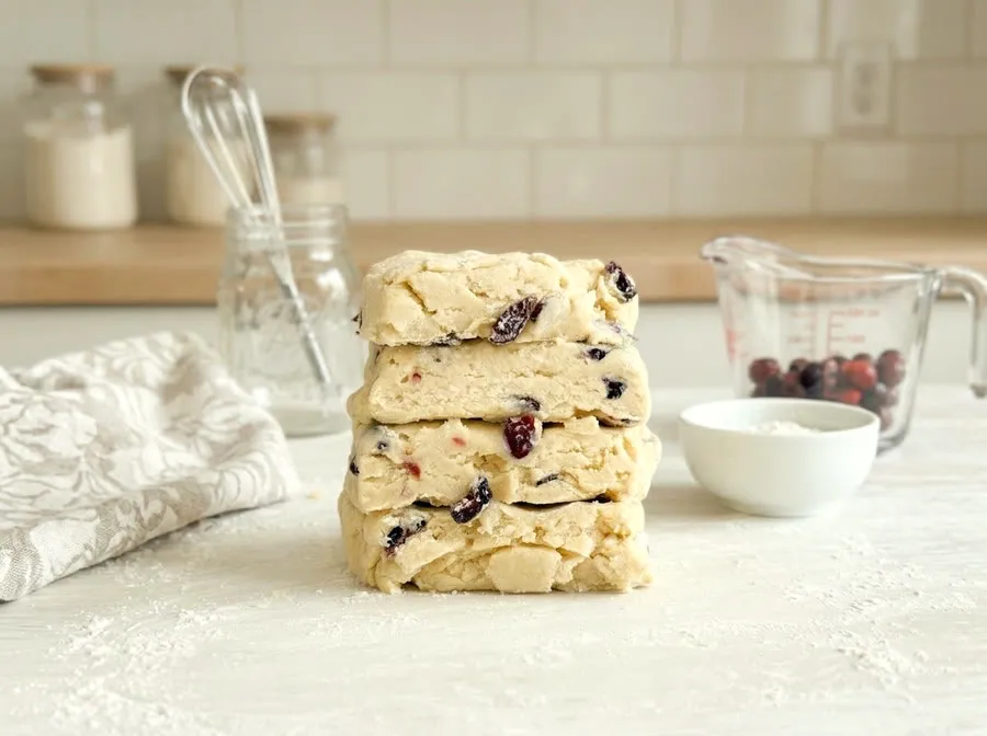 A block of laminated scone dough on a work surface, folded four times, the butter layers visible at the cut edge.